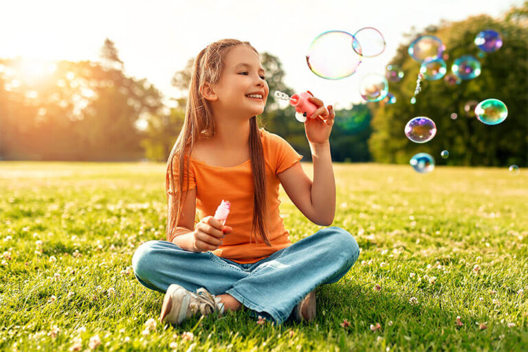 Cute beautiful girl blowing soap bubbles