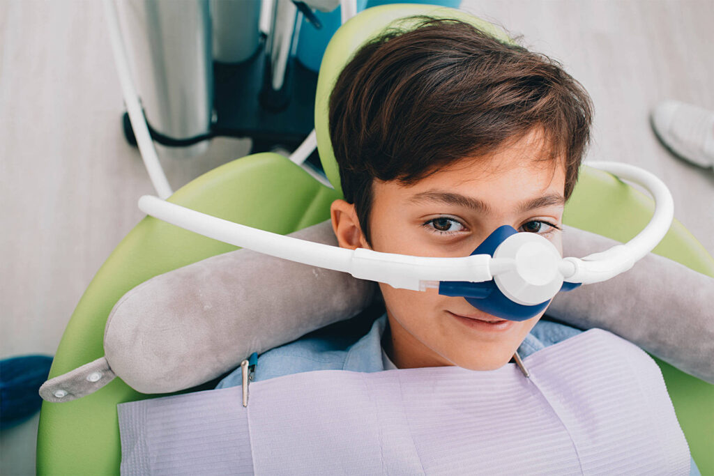 Little boy getting Inhalation Sedation while teeth treatment