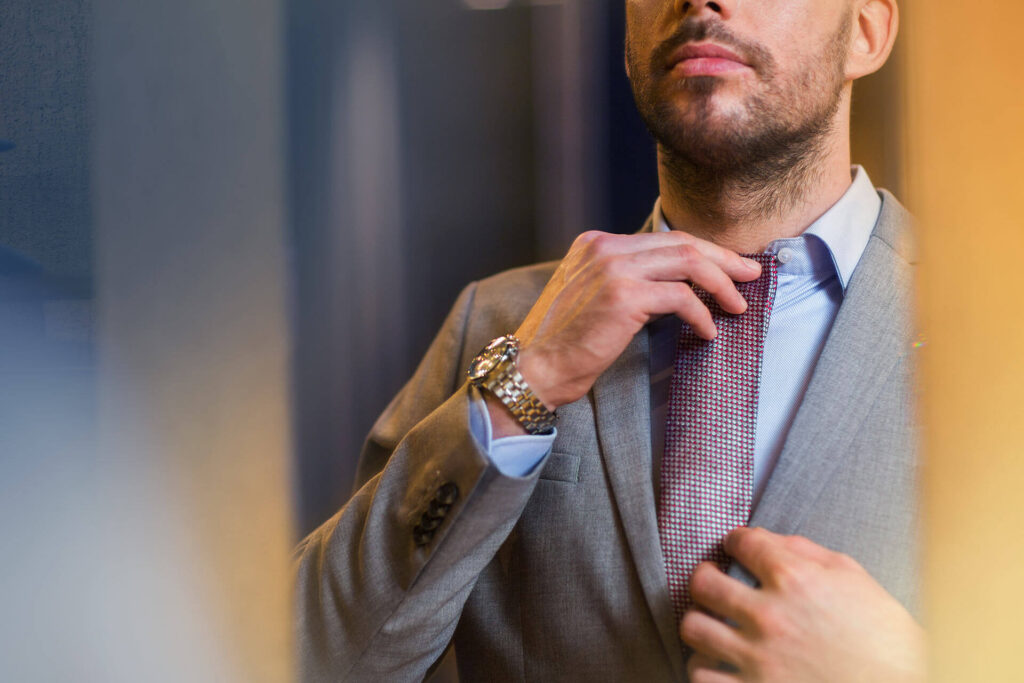 young man in suit choosing and trying tie