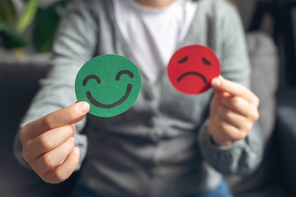 Selective focus of female hands holding happy and angry face paper