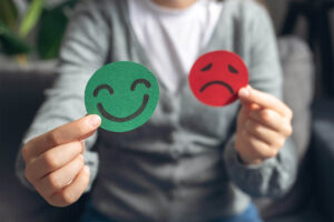 Selective focus of female hands holding happy and angry face paper