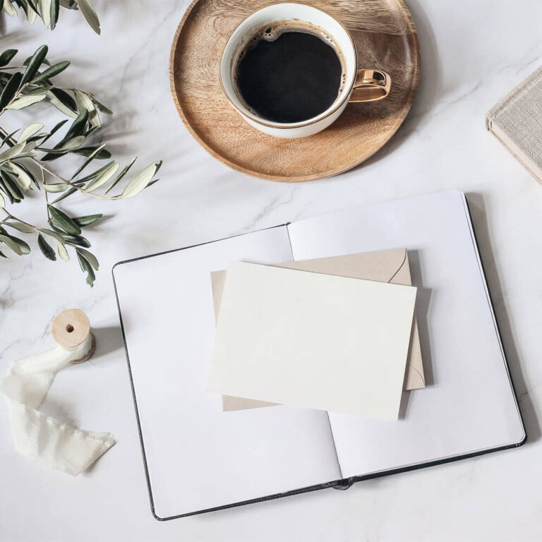 Open diary and blank greeting card mockups. Cup of coffee wooden plate, book, ribbon, olive leaves and branches