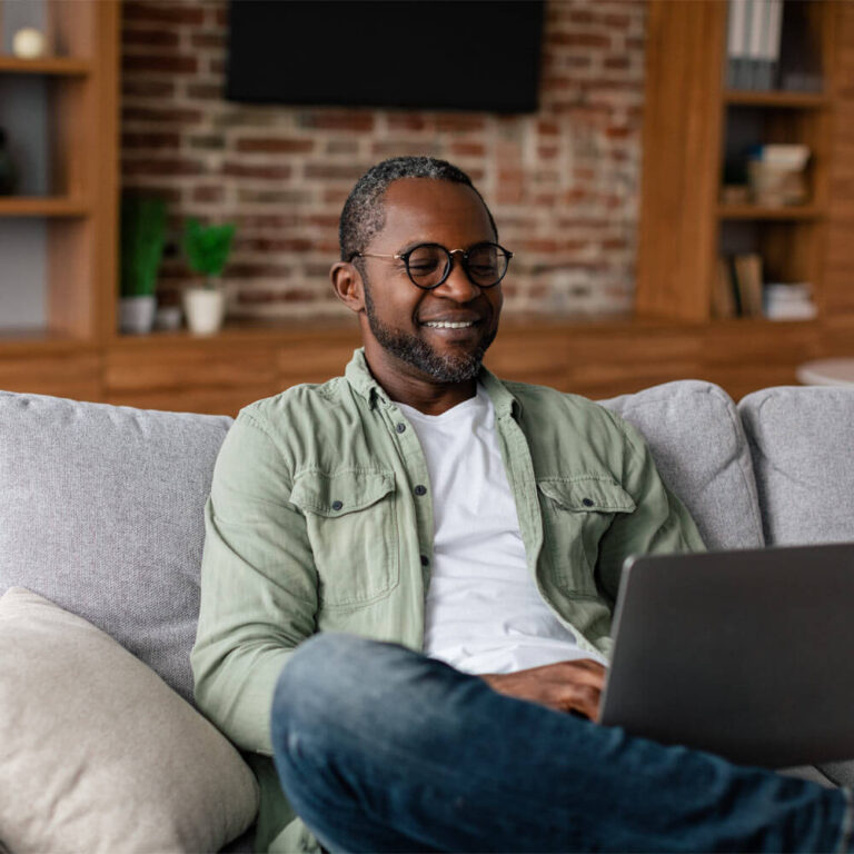 Happy adult male in glasses watching video on laptop