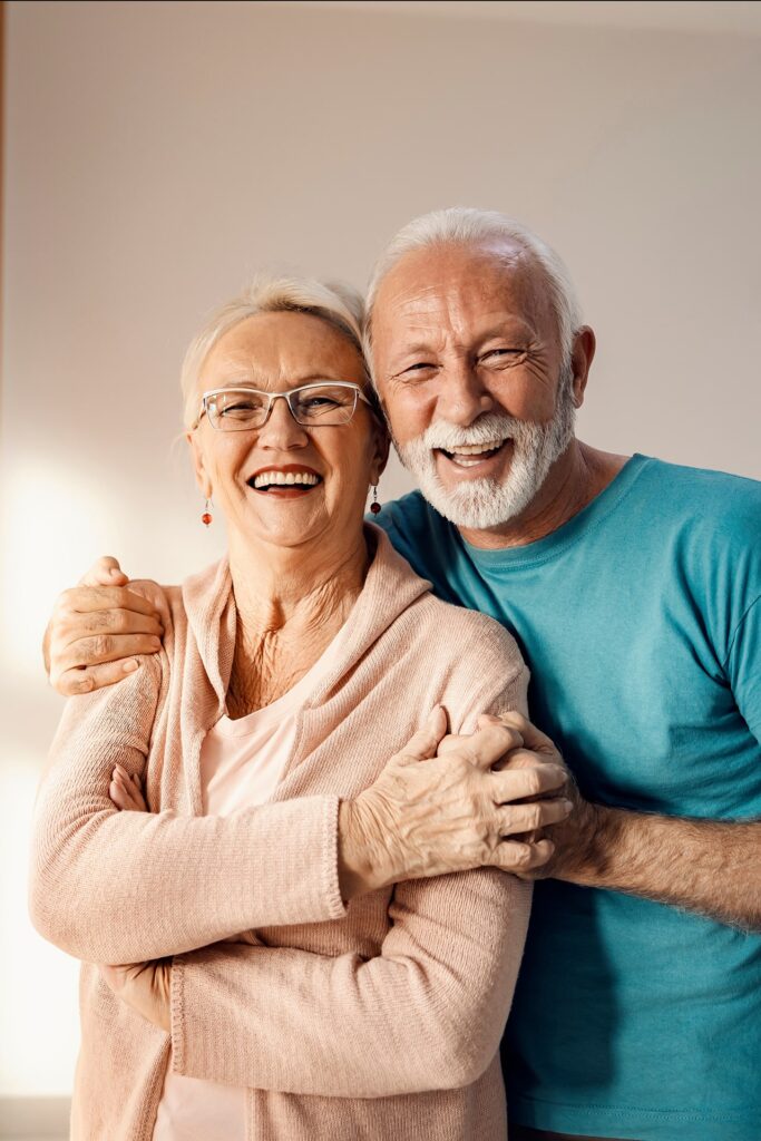 happy senior couple standing next to a window