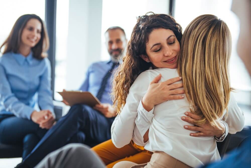 Young woman supporting friend during support group therapy