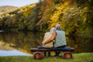 couple sitting on wooden bench watching the river