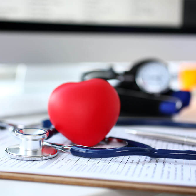 Stethoscope head and red heart shape toy lying on medical application form