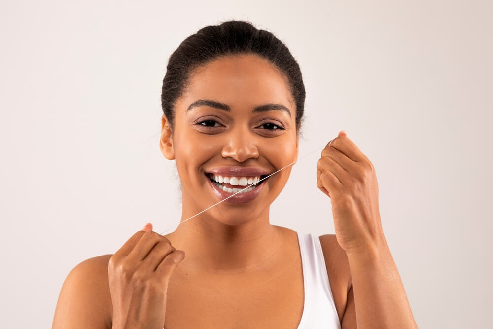 African american toothy female model flossing mouth