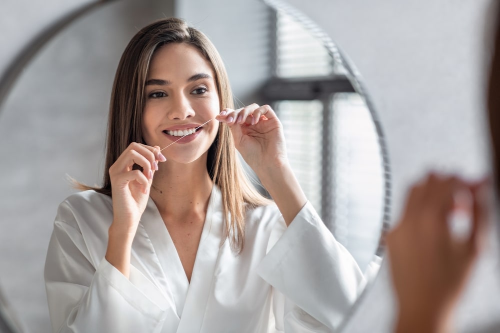 Smiling Young Female Using Dental Floss