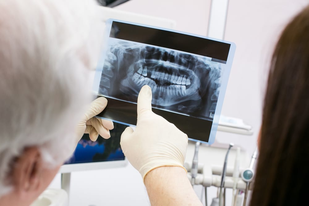 Dentist showing picture of female jaw while having appointment with her in clinic