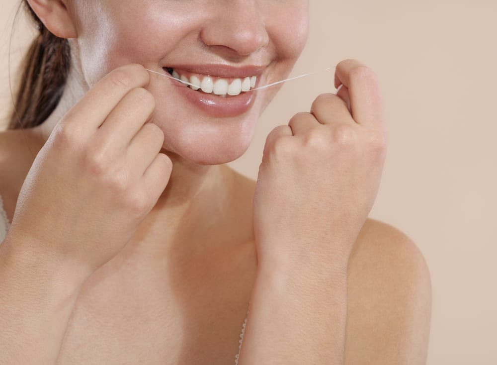 a young woman uses dental floss to clean your teeth