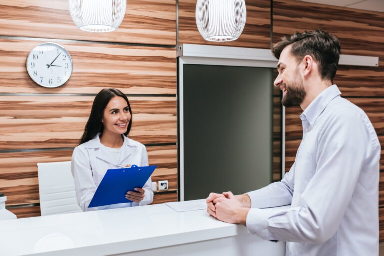 Young female doctor and handsome patient are standing on reception