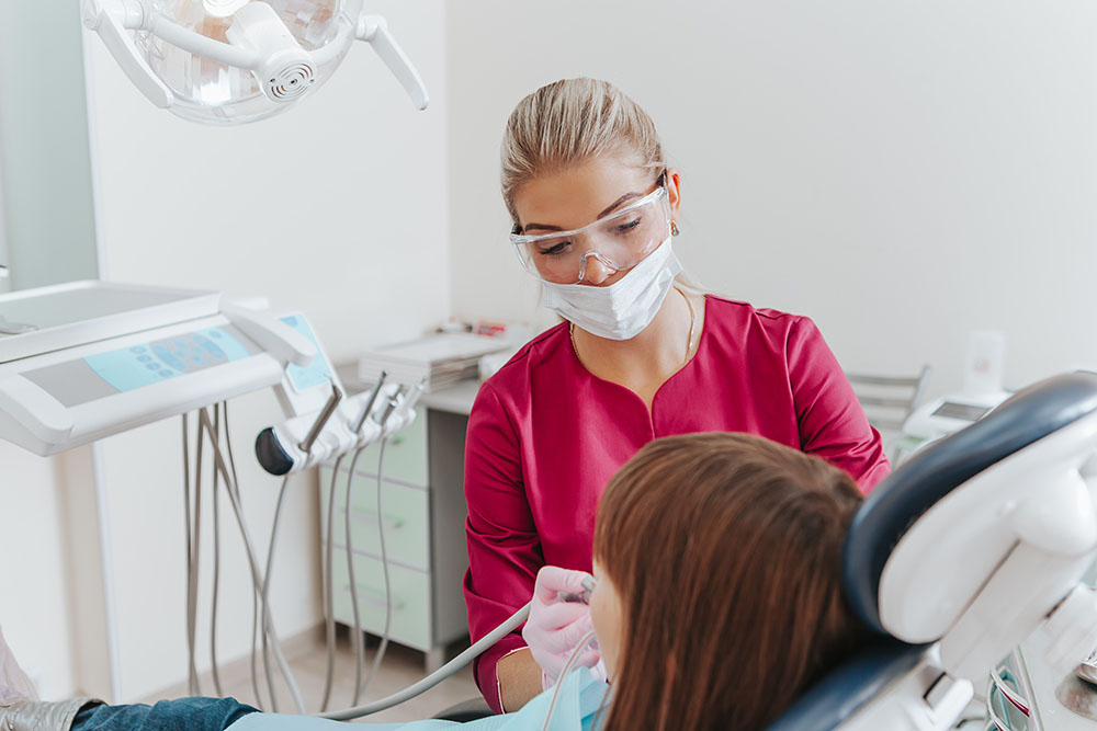 dentist in dental office treats teeth with kid patient