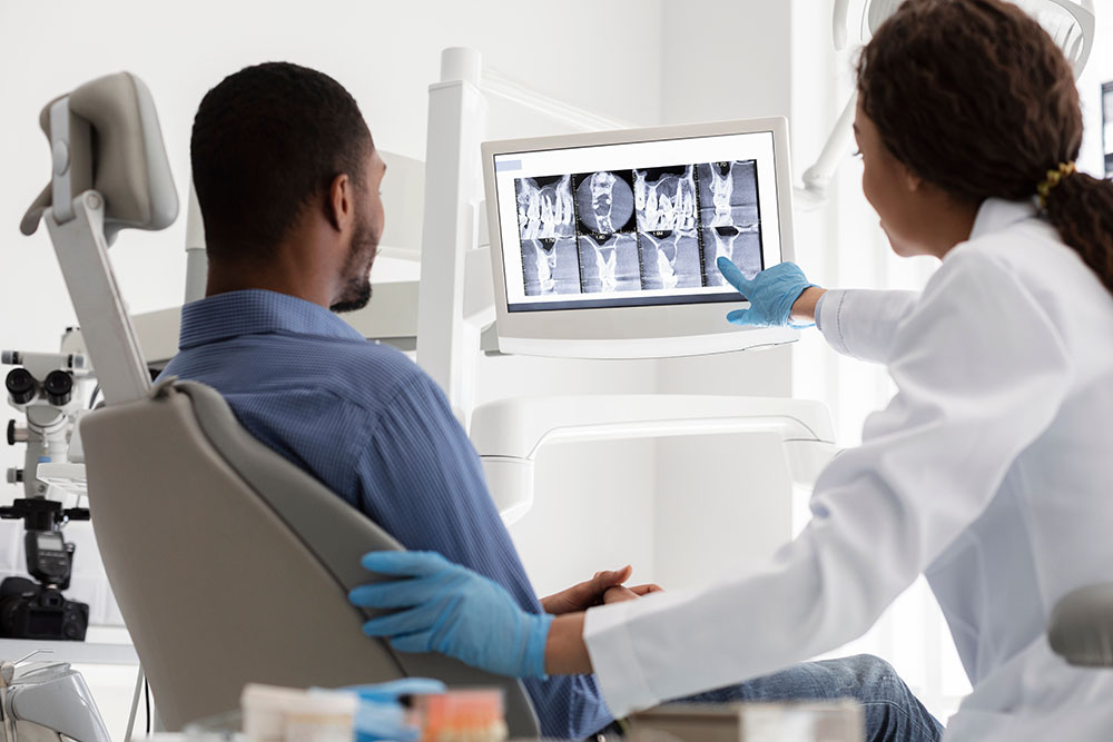 female dentist and male patient watching xray on digital screen