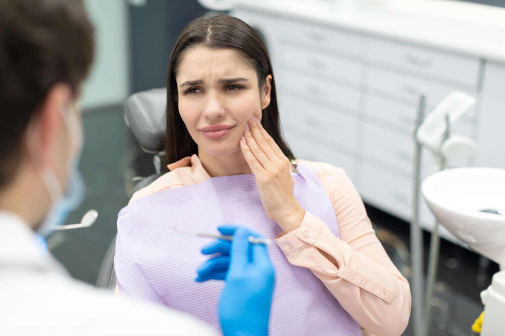 A woman at the dentist's office wondering if a broken root canal tooth is an emergency.