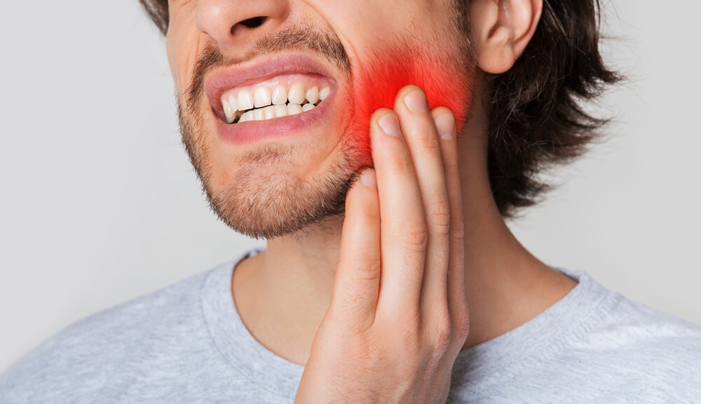 A man experiencing the worst day of pain after wisdom tooth extraction.
