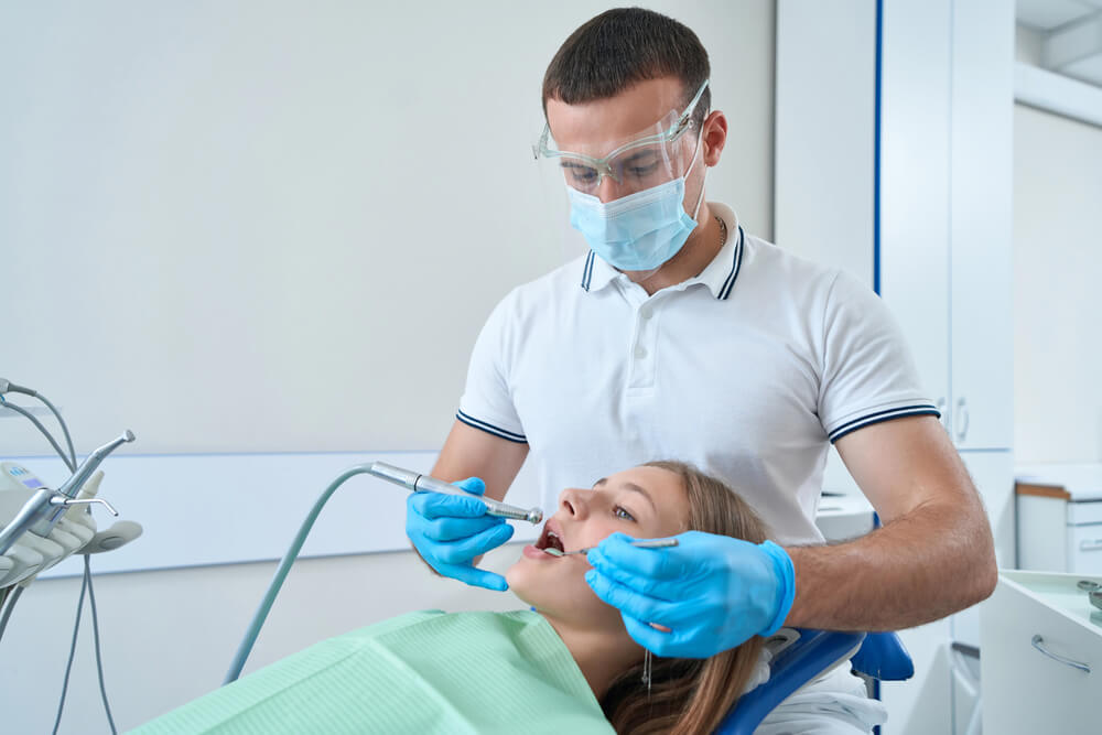 A young girl at the dentist, wondering how to relieve tooth pain after filling a cavity.