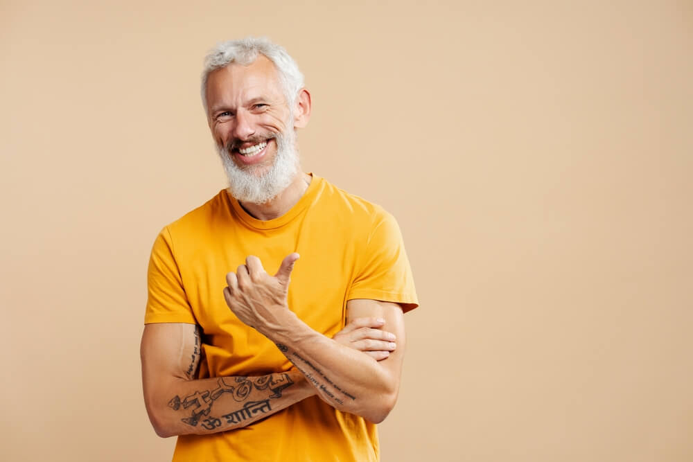 Attractive smiling mature man, gray haired bearded hipster wearing yellow t shirt