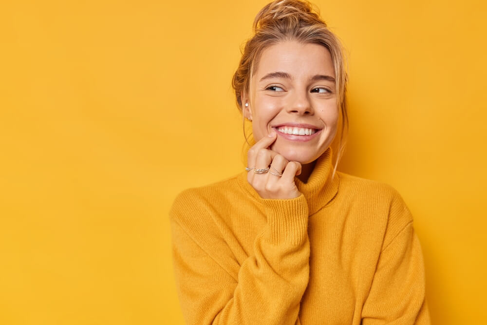 Beautiful glad woman smiles tenderly looks away