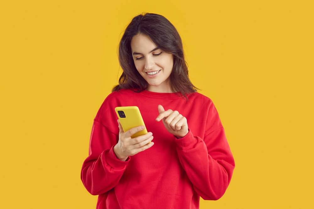 Smiling young woman texting on smartphone