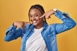 woman with braids standing over yellow background