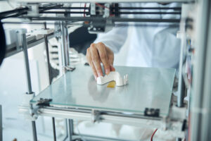 medical student in a lab coat examining the 3D printed denture