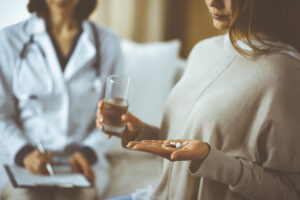Close-up woman-patient holding pills near her doctor, time to take medications,