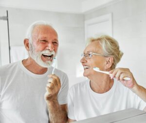 Portrait of an elderly senior couple cleaning brushing their teeth in front of mirror in bathroom