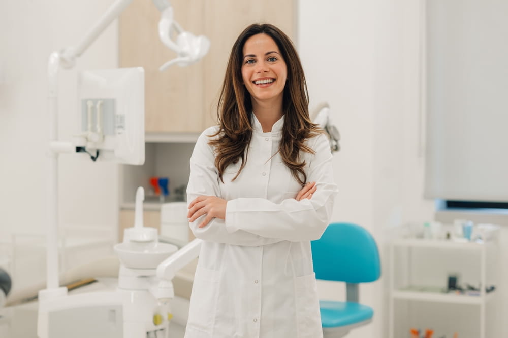Confident female dentist smiling with crossed arms