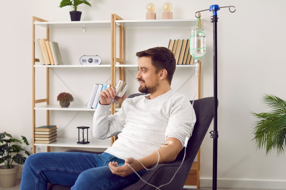 Dehydrated young man receiving intravenous vitamin therapy in hospital room