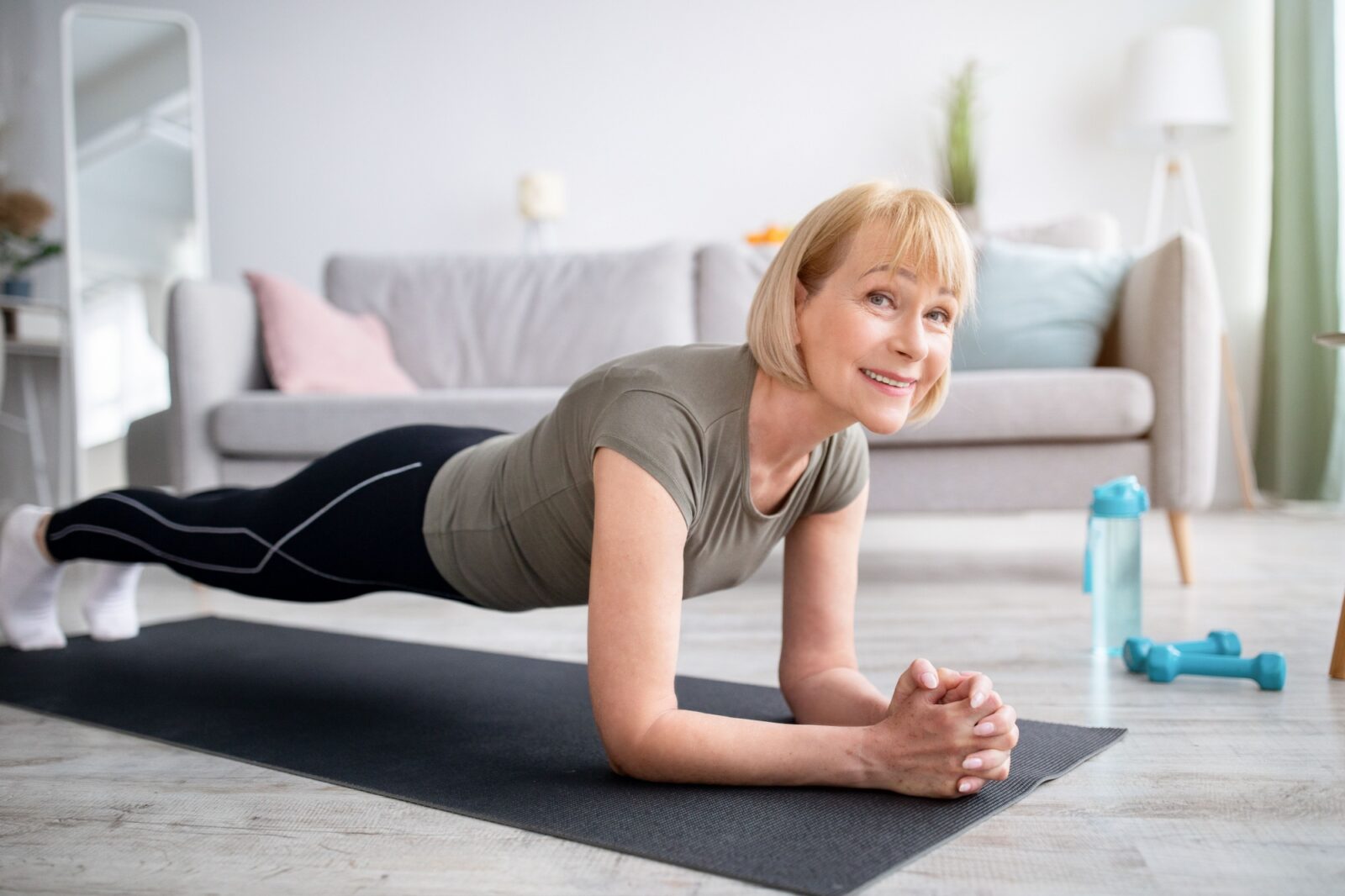 Smiling senior woman doing elbow plank on yoga mat