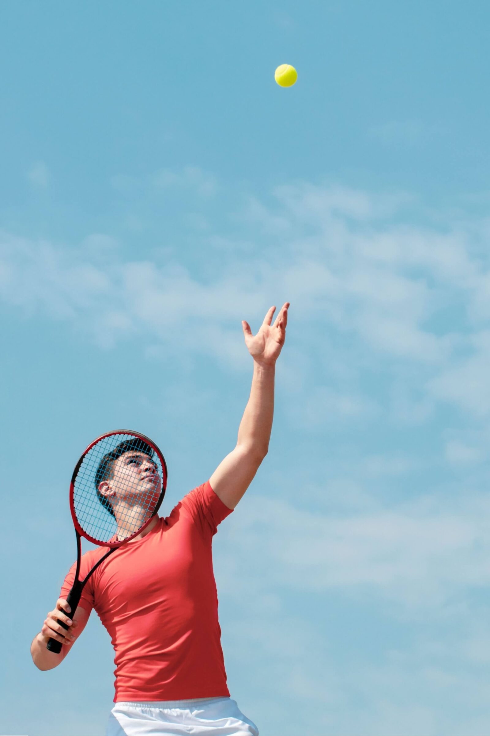 Young tennis player with racket throws the ball