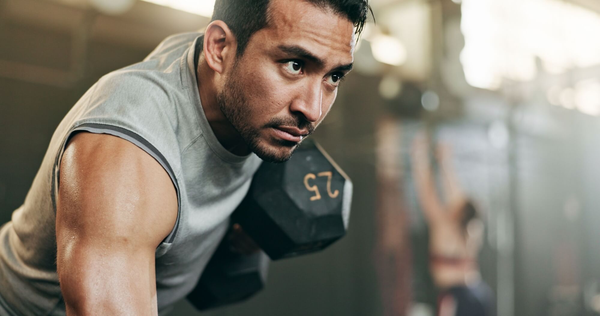 Active male person weightlifting for fitness at indoor gym