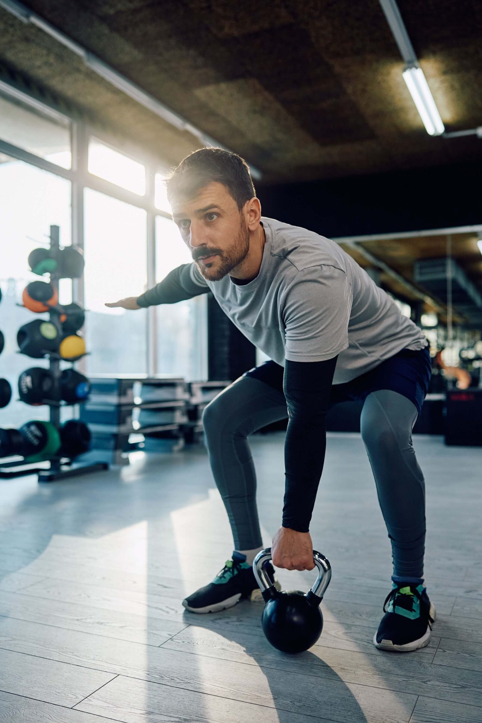 Athletic man exercising with kettlebell while working out in health club