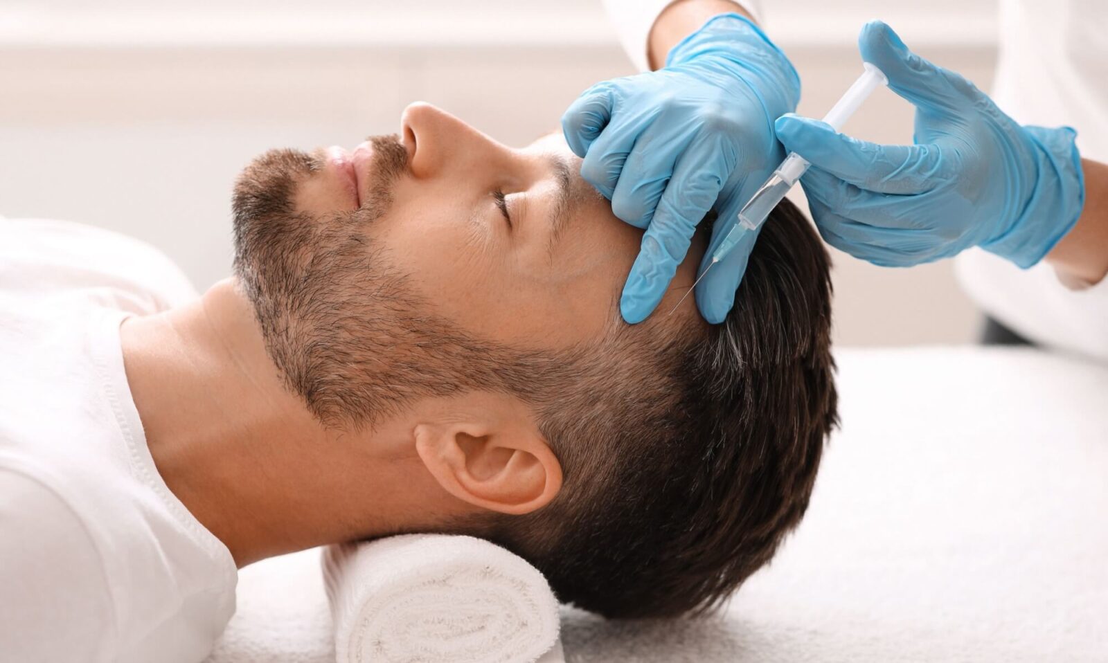 Handsome middle aged man getting hair treatment at beauty salon