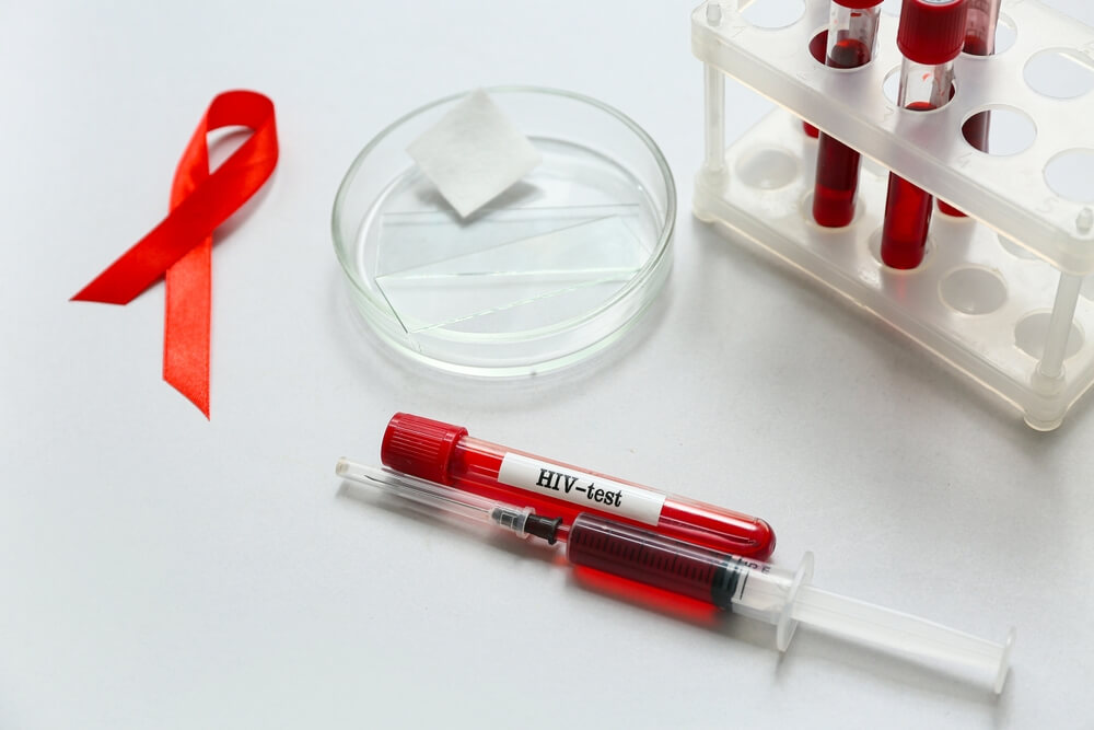 HIV blood test tubes, syringe and red ribbon