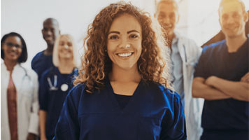 Smiling female doctor standing in a hospital with group of medical staff