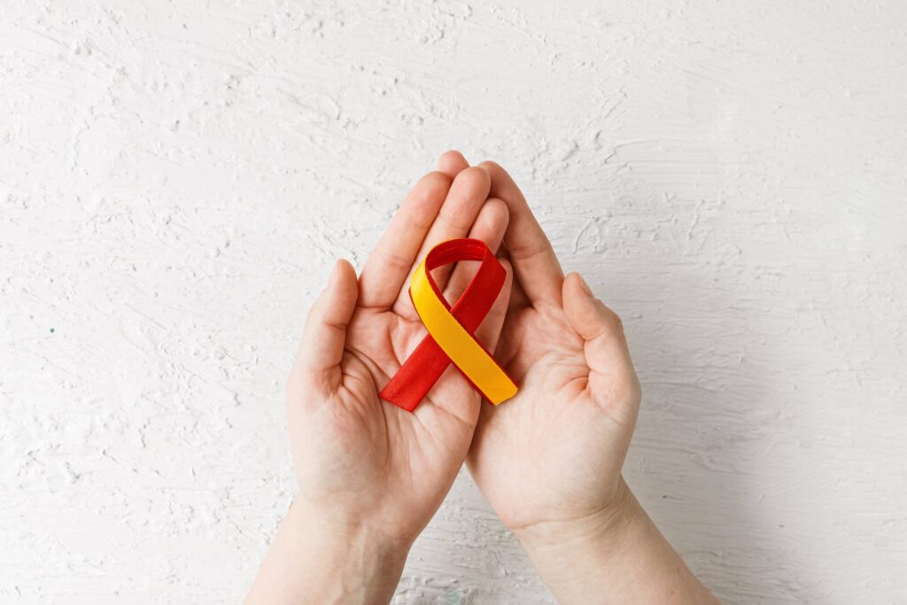 hands holding red yellow ribbon, Awareness of prevention and treatment viral hepatitis