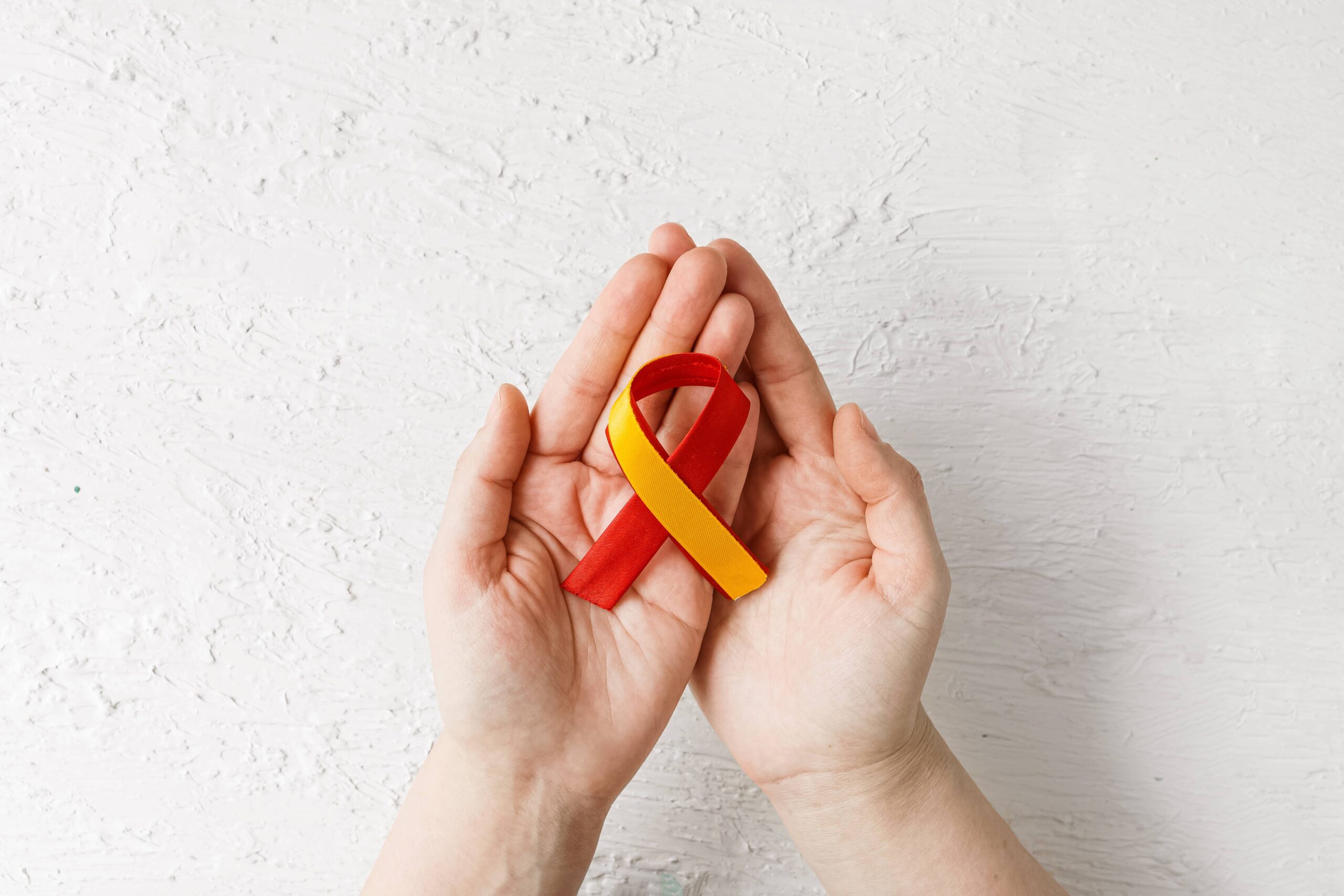 hands holding red yellow ribbon, Awareness of prevention and treatment viral hepatitis