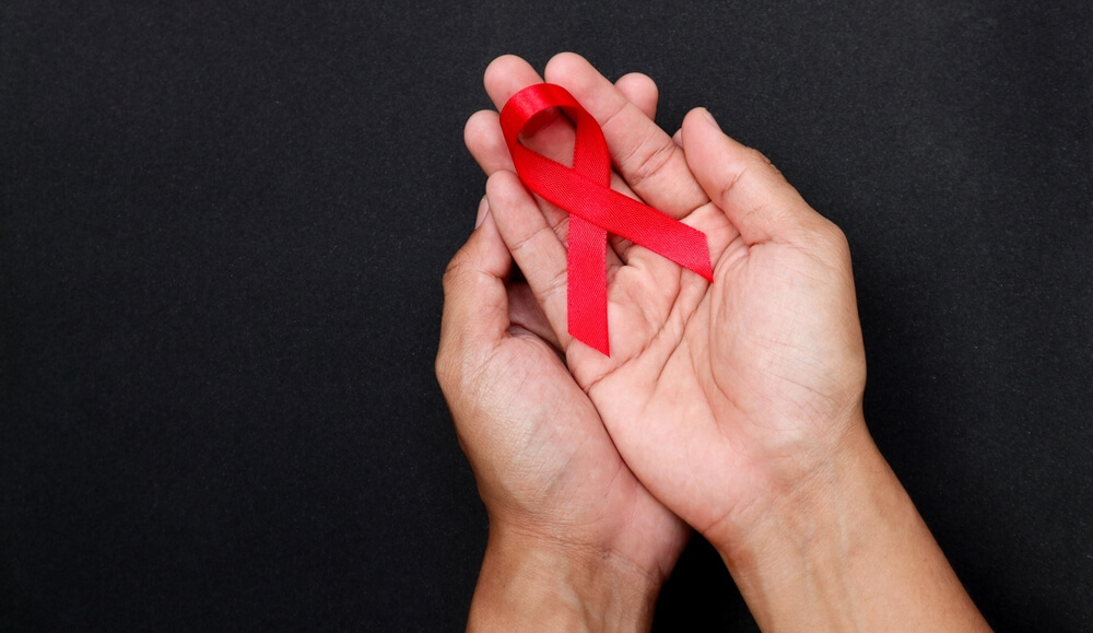 Holding red ribbon in honor of HIV awareness