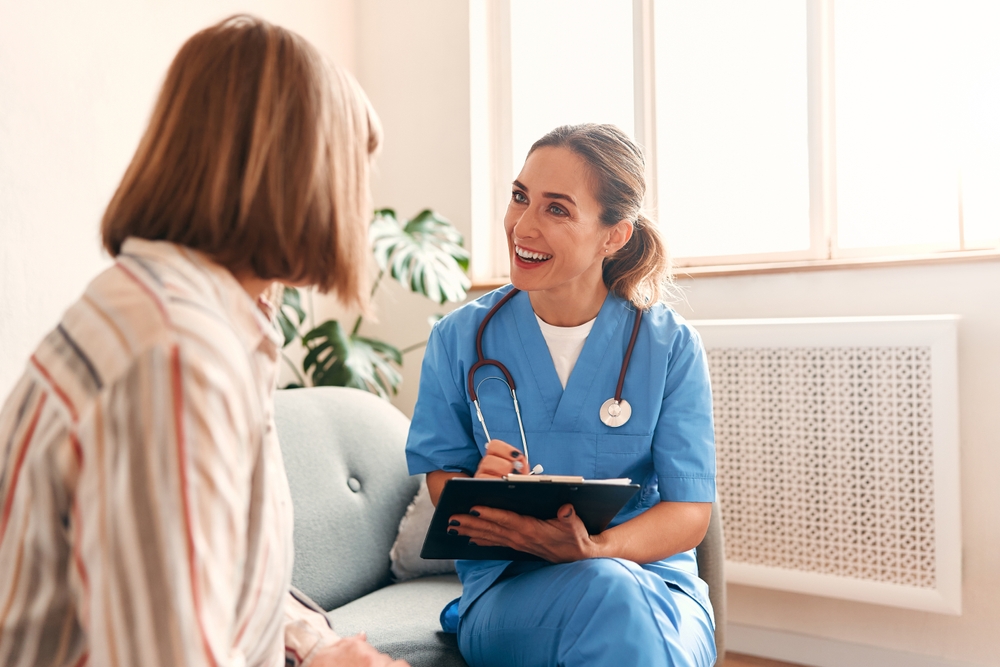female nurse provide care medical service help support smiling mature woman at homecare medical visit