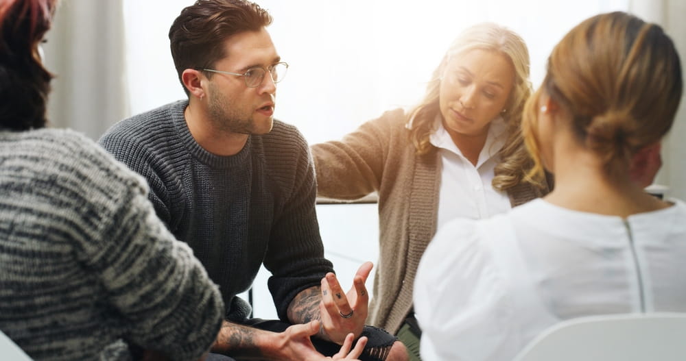 Support, group counseling and sad man in circle for addiction recovery, share story or comfort