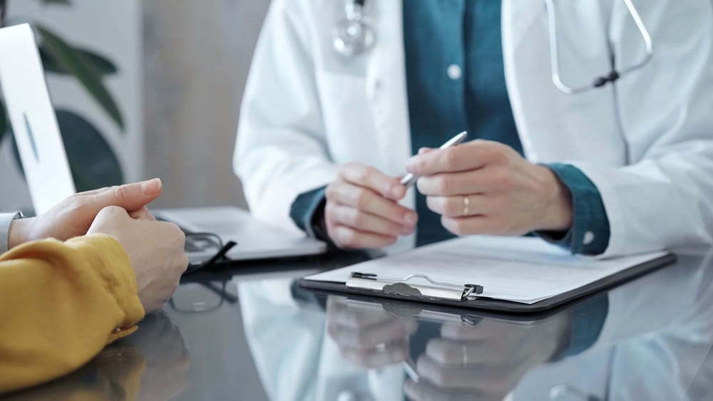 Doctor and patient consultation in clinic. Patient listens attentively as a doctor explains a diagnosis in a modern medical office