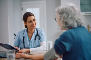 Happy visiting nurse communicating with senior woman at home.