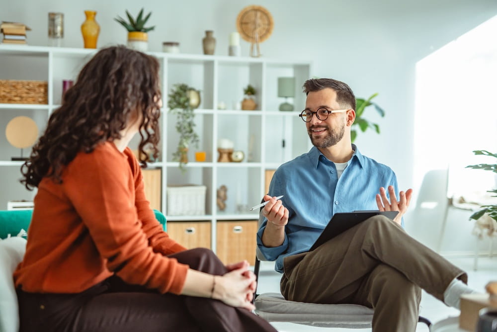 Young woman receiving support and advice from a male psychologist, engaging in a therapy session for mental health