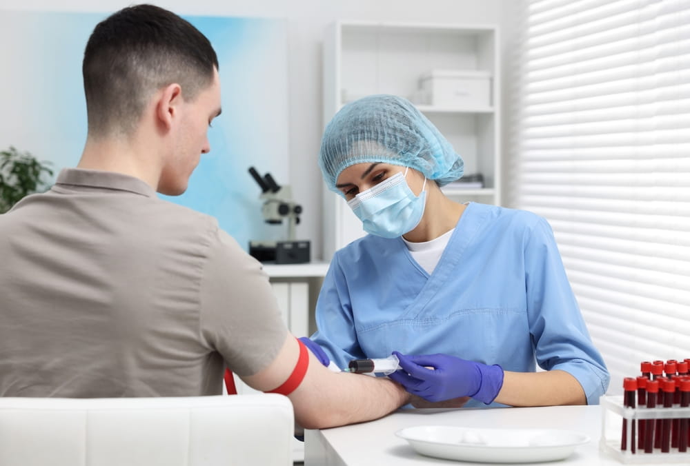 Laboratory testing. Doctor taking blood sample from patient at white table in hospital