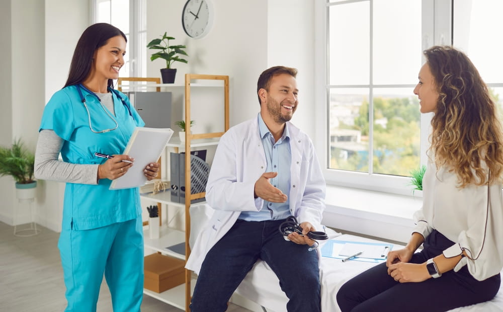 Male doctor and nurse engage in consultation with a patient in the hospital office.