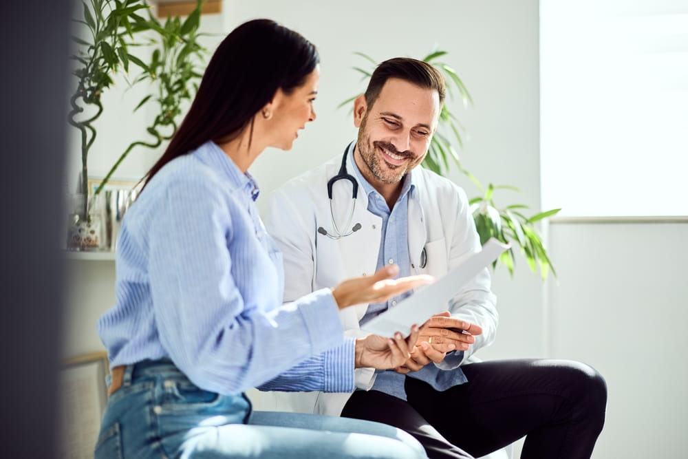 A doctor is engaged in a positive conversation with a patient, reviewing a medical document together.