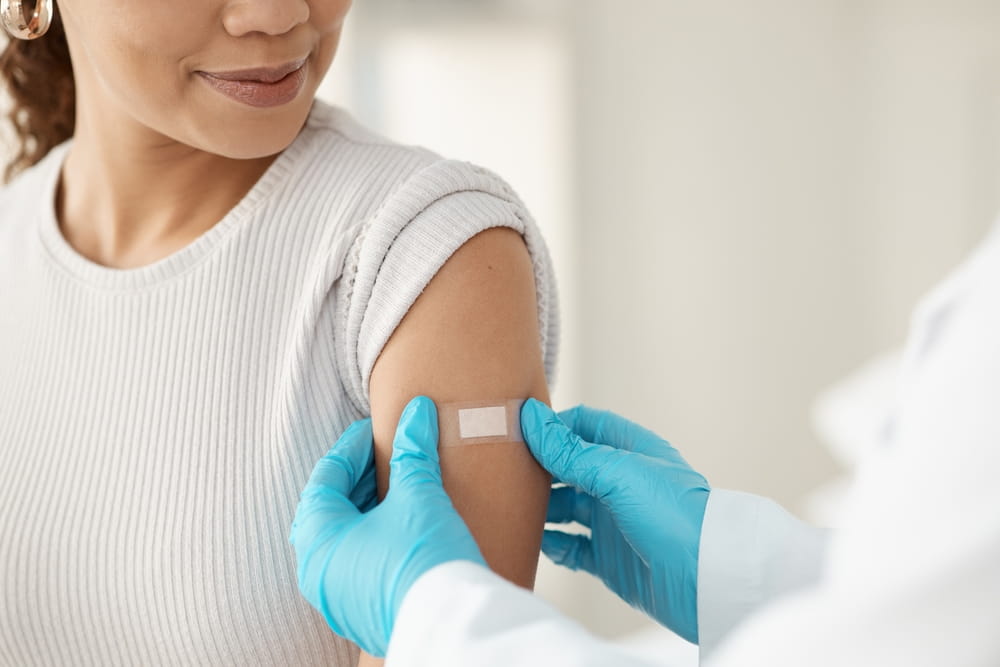 Vaccine, happy woman and hands of doctor with plaster for health, wellness and service in clinic