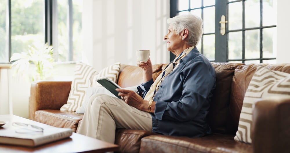 Coffee, tablet and think with old woman in home for movie choice, relax or daydream in retirement.